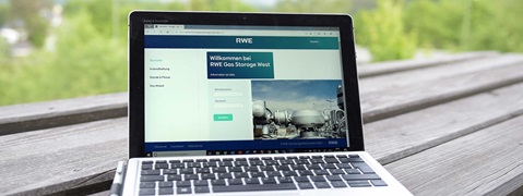 Das Bild zeigt ein Laptop, der eine Webseite von RWE Gas Storage West anzeigt, vor einer grünen, bewaldeten Kulisse.