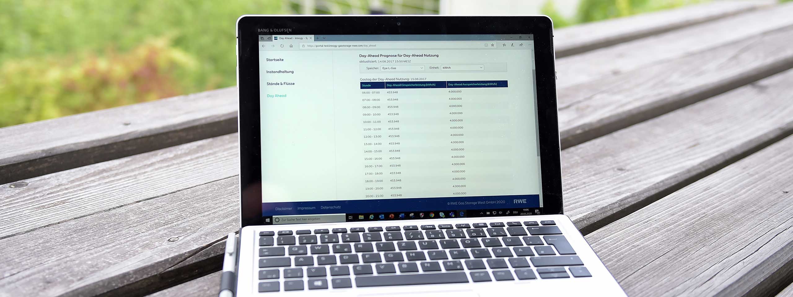 A laptop on a wooden table displays a webpage with energy usage data and forecast information.